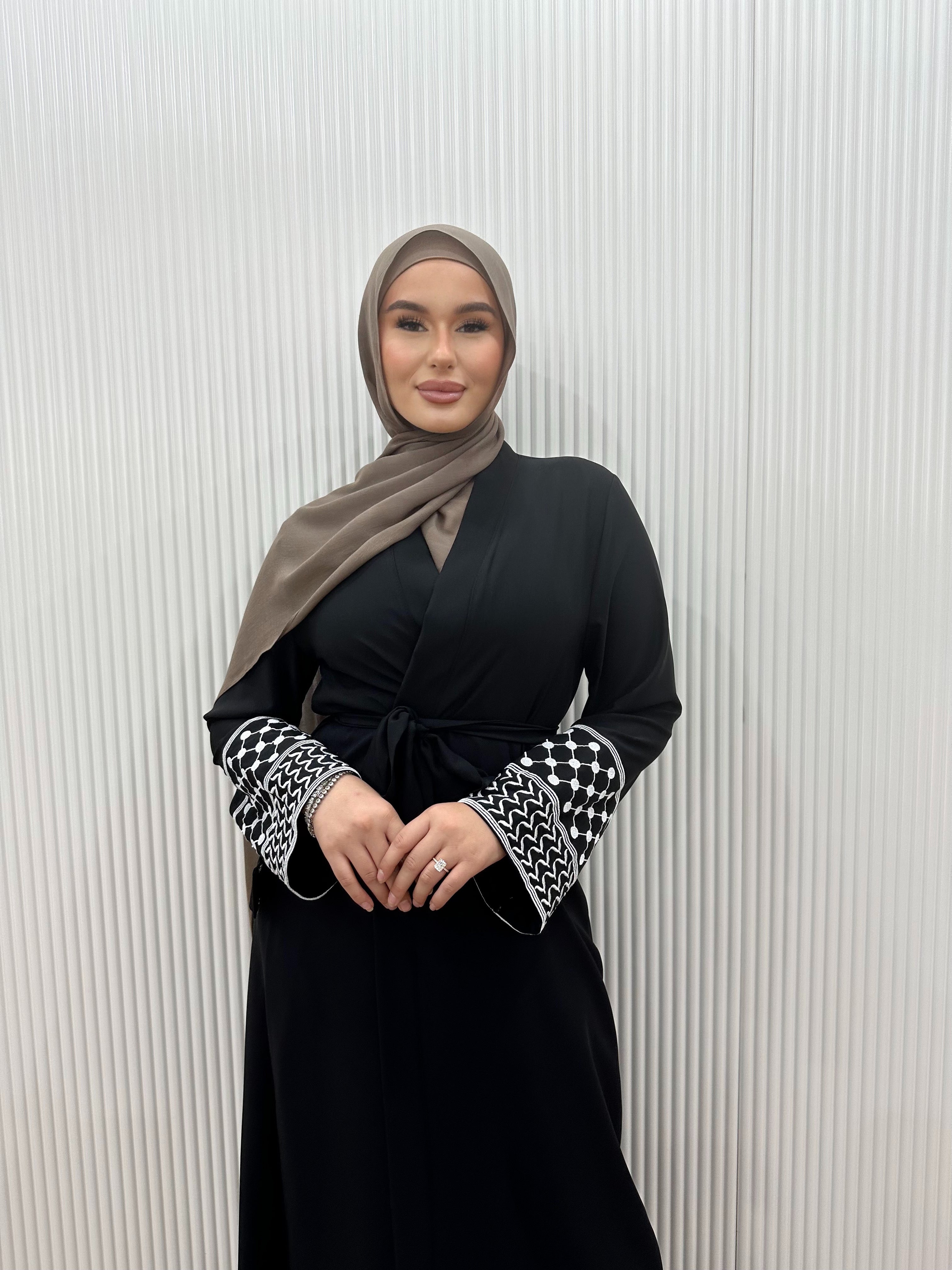 Show your support for Palestine with the KEFFIYEH SLEEVE ABAYA. With signature Palestinian craft printed on the wide sleeve cuffs, this dress effortlessly combines modesty and comfort. The wrap-inspired silhouette features a self-fastening tie wrap, maxi length hem. Wear yours to public social gatherings to show where you stand!&nbsp;
