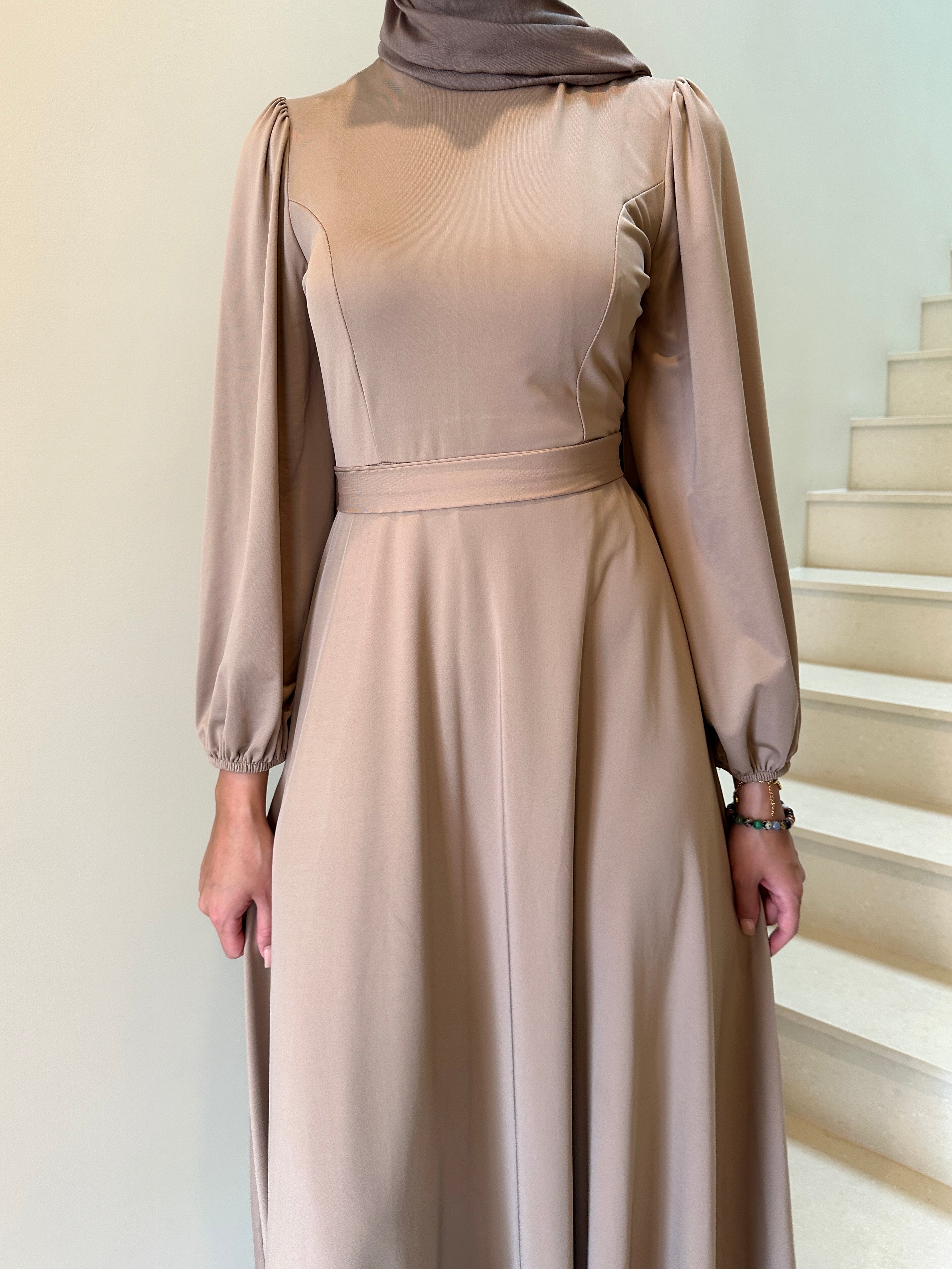 It has long sleeves and a fitted bodice with limited stretch, then drops from an empire cut waist to a loose high low skirt.