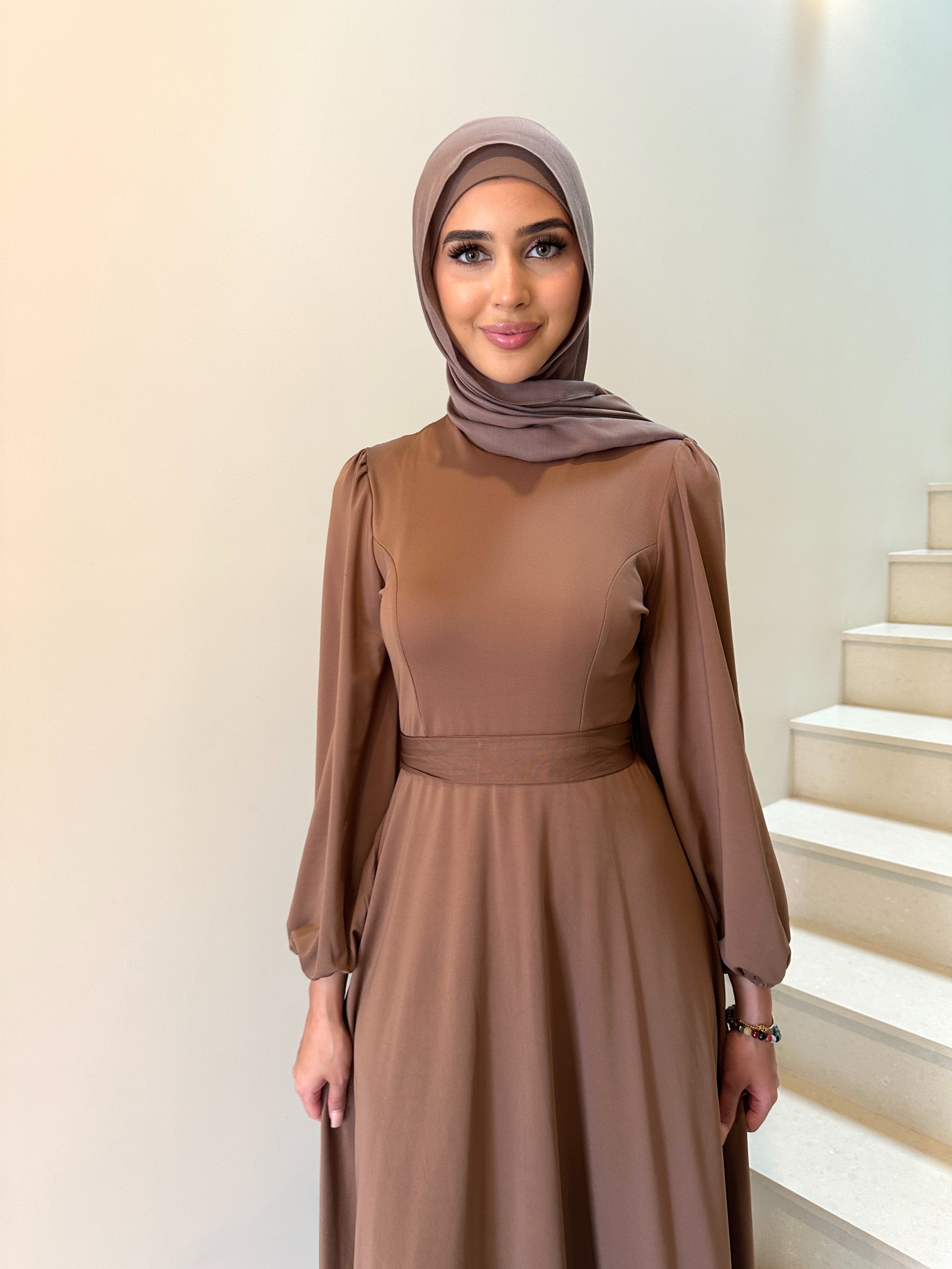 It has long sleeves and a fitted bodice with limited stretch, then drops from an empire cut waist to a loose high low skirt.