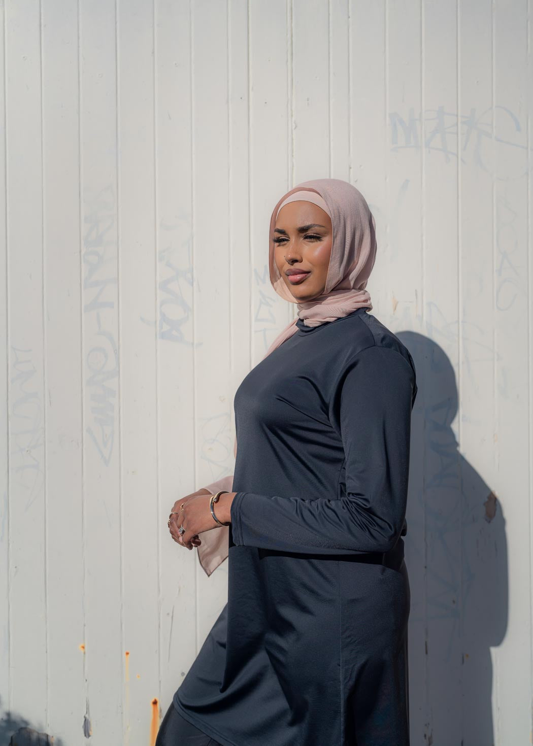 Model wearing the Marina modest swimwear set in black or mauve, featuring a long-sleeve top that falls above the knee and loose trousers with an elasticated waistband. Made from stretch scuba fabric (85% polyester, 15% elastane) for a comfortable fit.