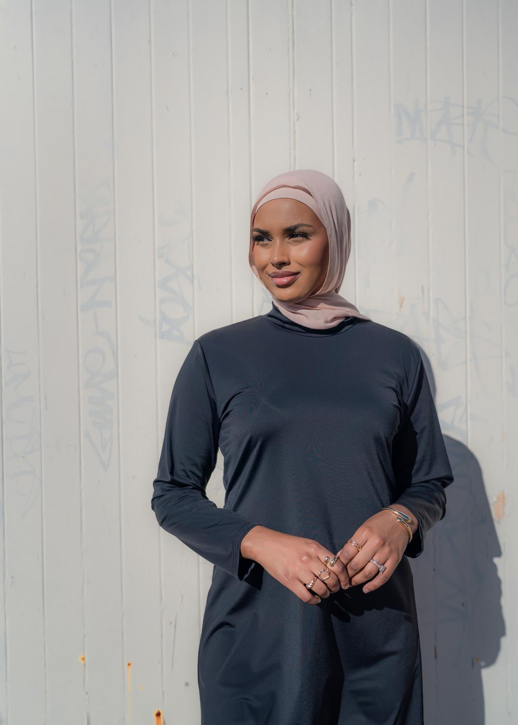 Model wearing the Marina modest swimwear set in black or mauve, featuring a long-sleeve top that falls above the knee and loose trousers with an elasticated waistband. Made from stretch scuba fabric (85% polyester, 15% elastane) for a comfortable fit.