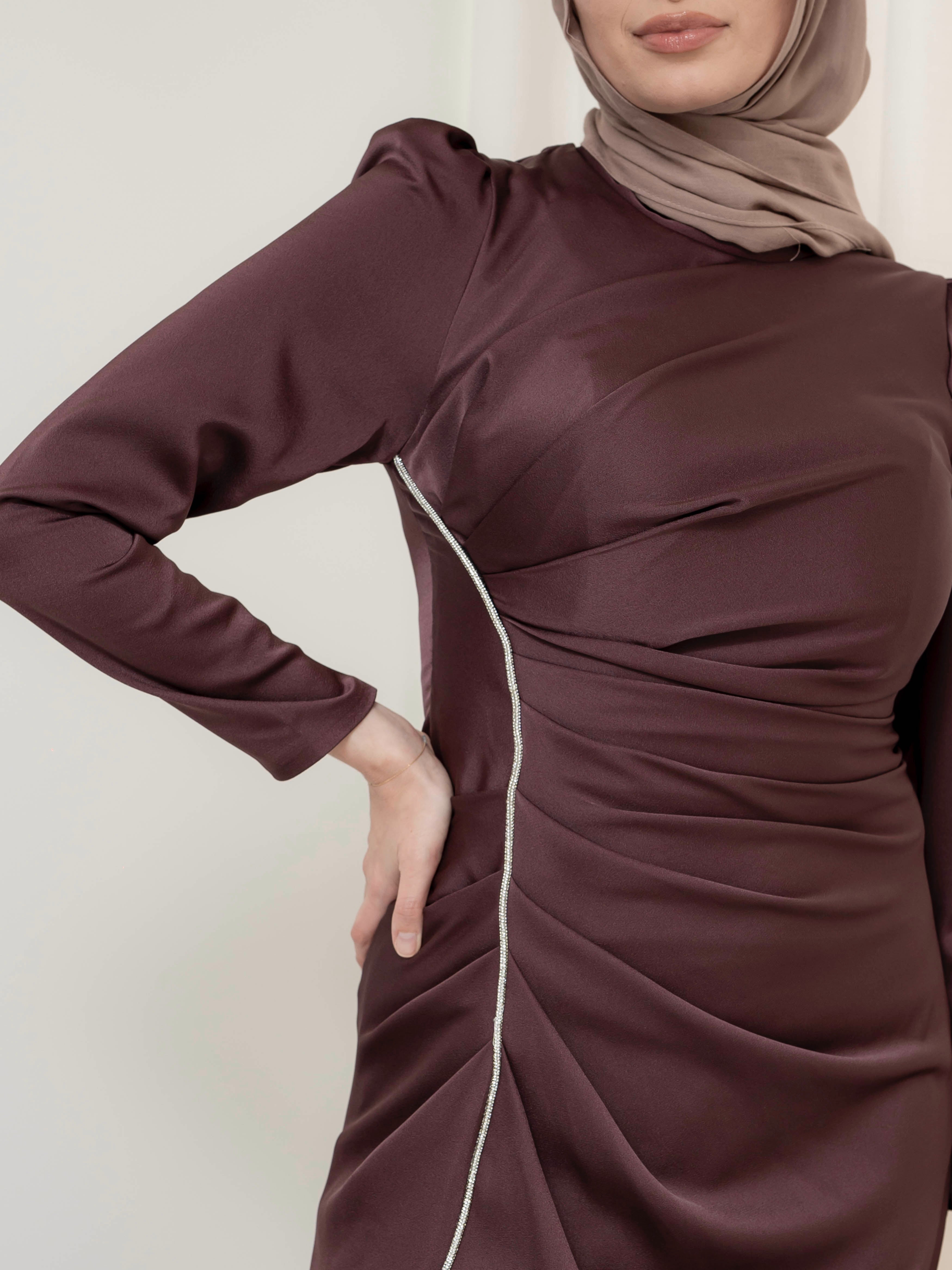 Elevate your formal look with the OLA FORMAL DRESS- MAHOGANY. Crafted from a shiny satin crepe fabric, this dress boasts elegant asymmetric gathers and a flattering silhouette that will make you stand out. Complete with long slim sleeves and a floor-skimming hem, this dress is perfect for any formal occasion.