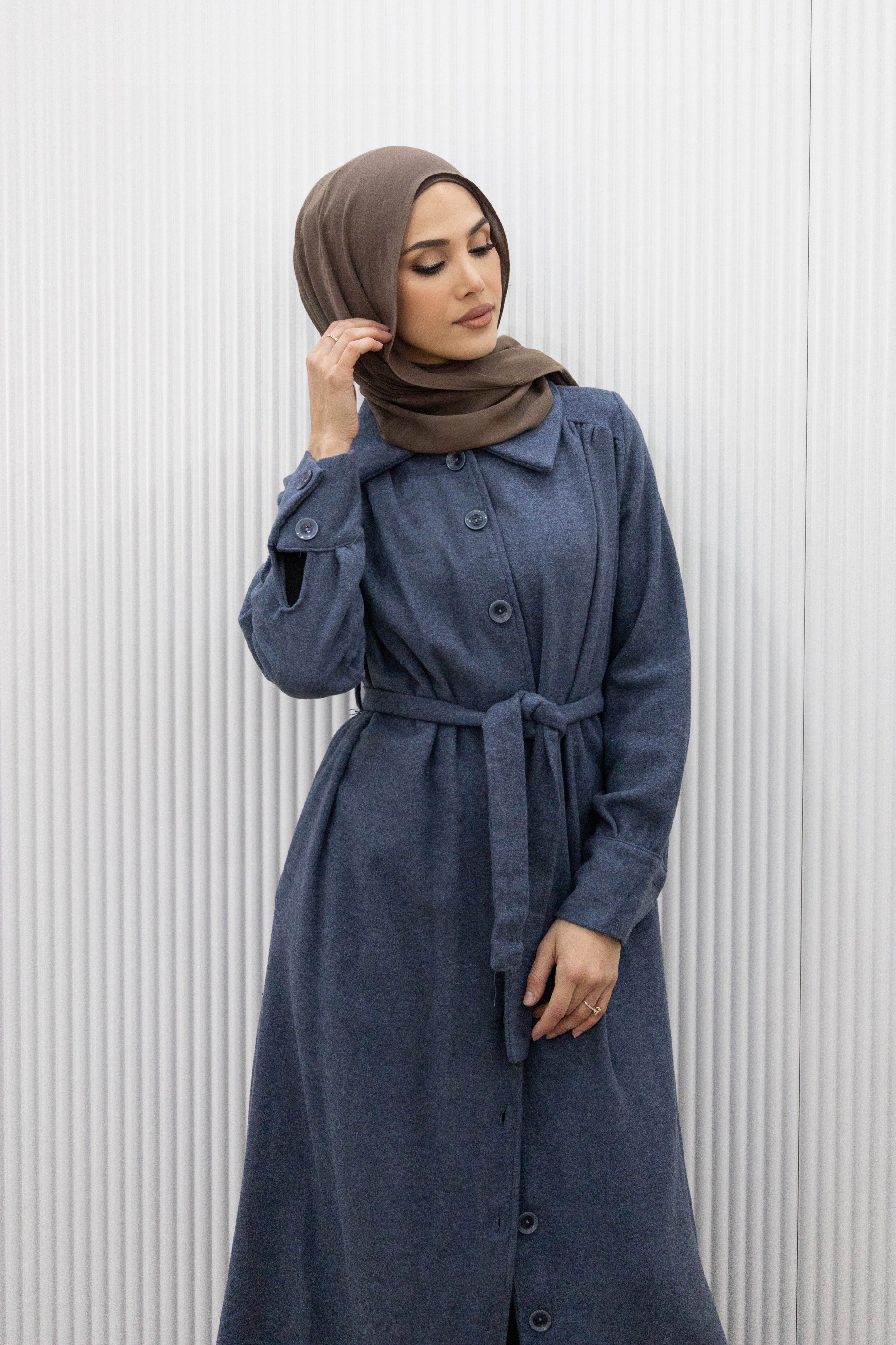 This buttoned maxi coat not only exudes elegance, but also offers practicality with a detachable waist tie for a fitted look. The wide collar and long sleeves with buttoned cuffs complete the full length silhouette, keeping you warm and stylish all season long.