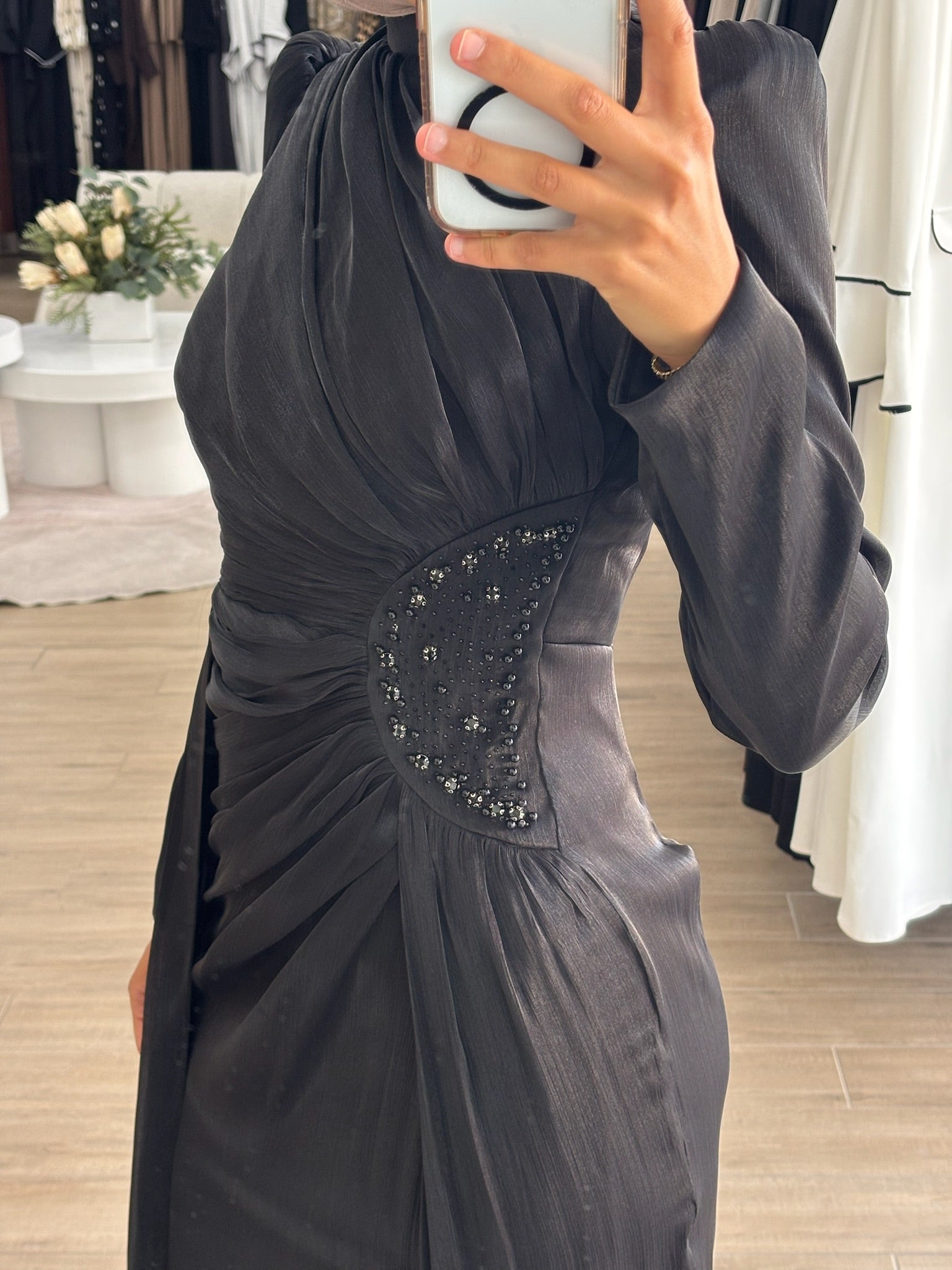 Reanne Formal Dress in glossy satin with a flattering ruched silhouette, high neckline, and long sleeves. Features embellished waist detailing, a draped floor-length panel, invisible back zip, and full lining — perfect for elegant formal occasions.