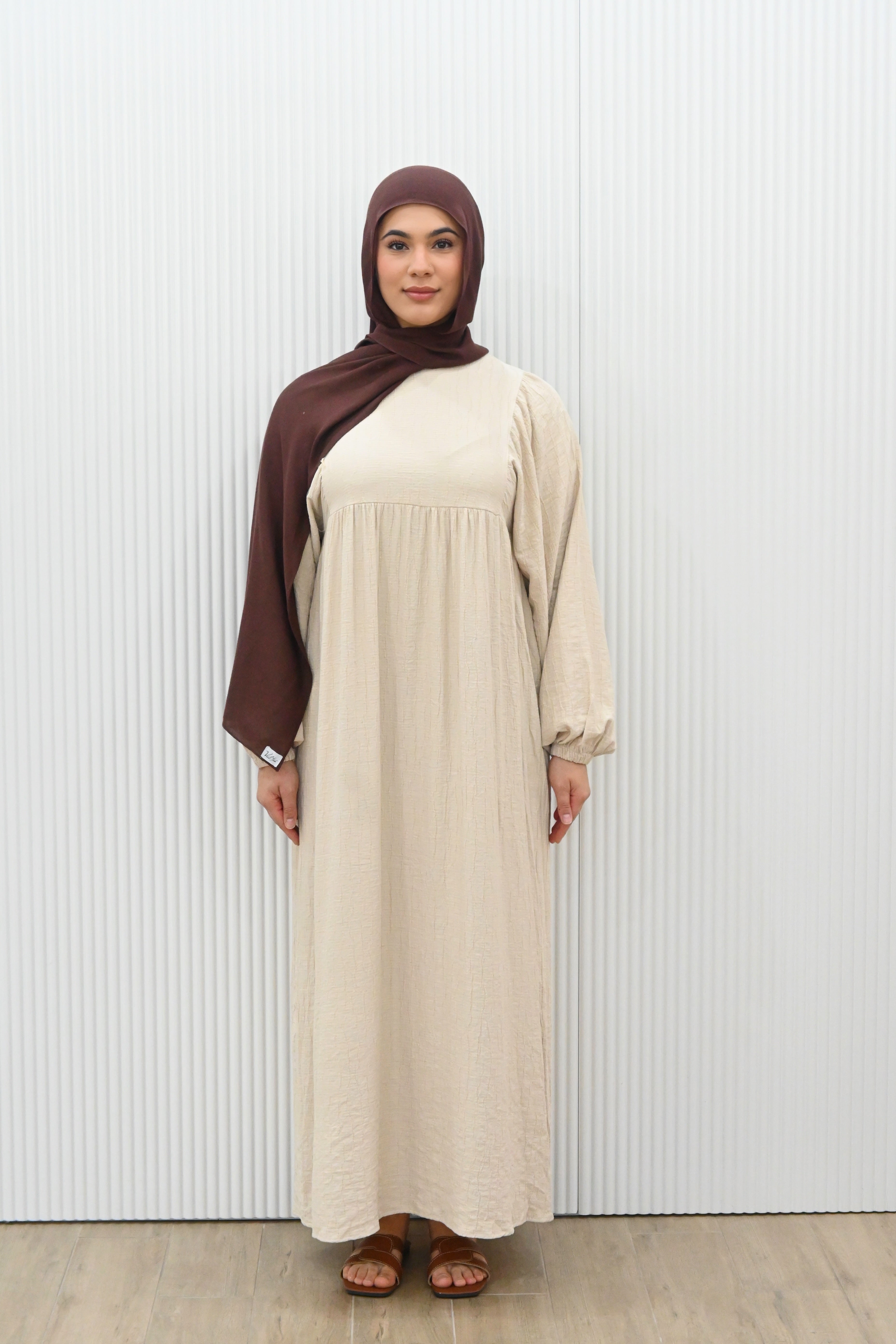 Sakina Dress in a loose, flowy summer style with long sleeves, paired with a brown hijab and brown sandals. Generous fit for comfortable, modest wear.