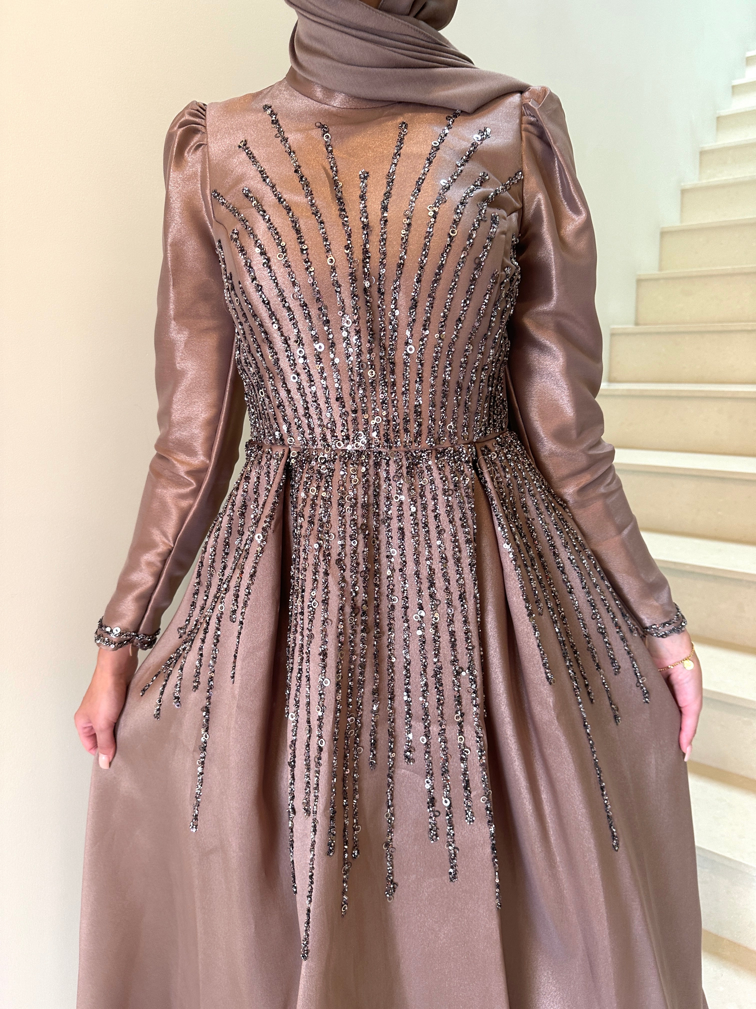 Shaima Formal Dress in shiny satin with a fitted waist and ball gown skirt. Features high neck, puffy shoulders, long sleeves, and sequined embellishments on bodice and skirt with an invisible back zip — perfect for formal occasions.