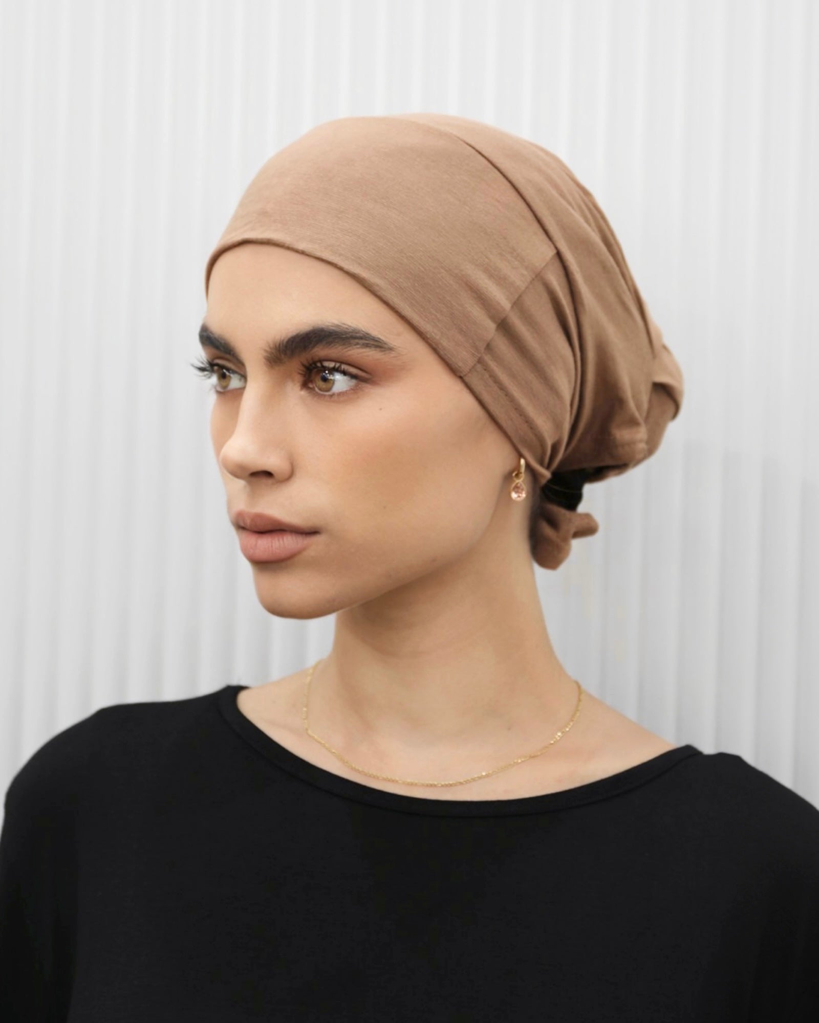 Tie Back Cap in bronze colour, featuring an adjustable strap at the back for a comfortable fit.