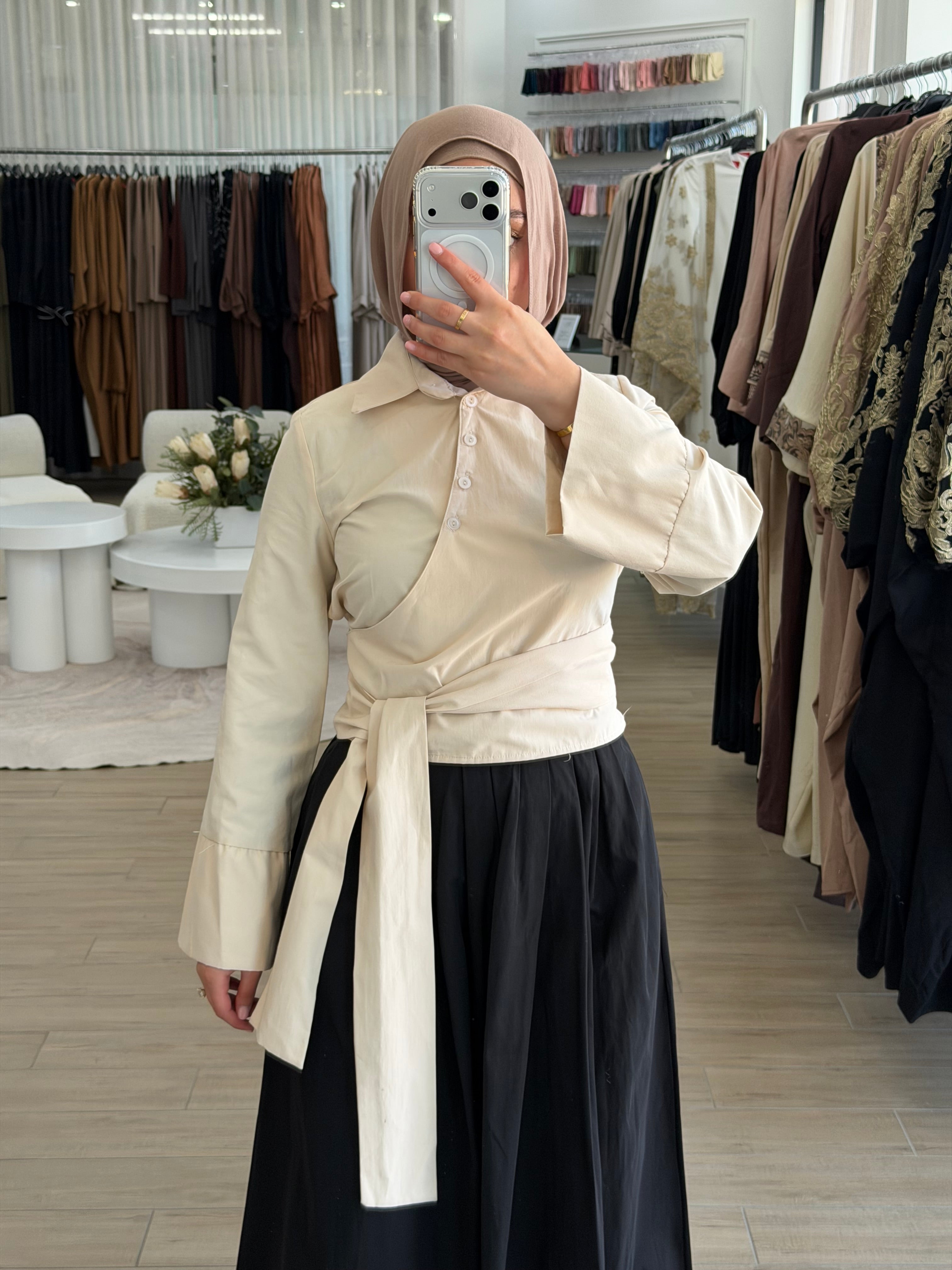 Woman wearing a Manal wrap shirt with a button-down front, asymmetric wrap panel, and cropped hem.