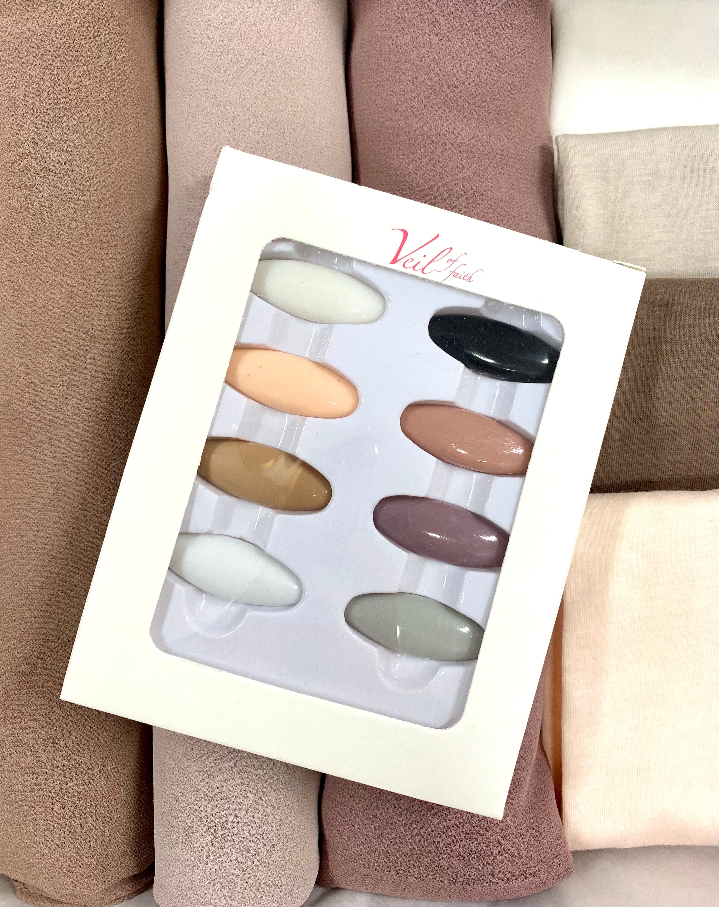 A set of Hijab pins displayed in a box, with a variety of colors including black, brown, silver, gold, and white.