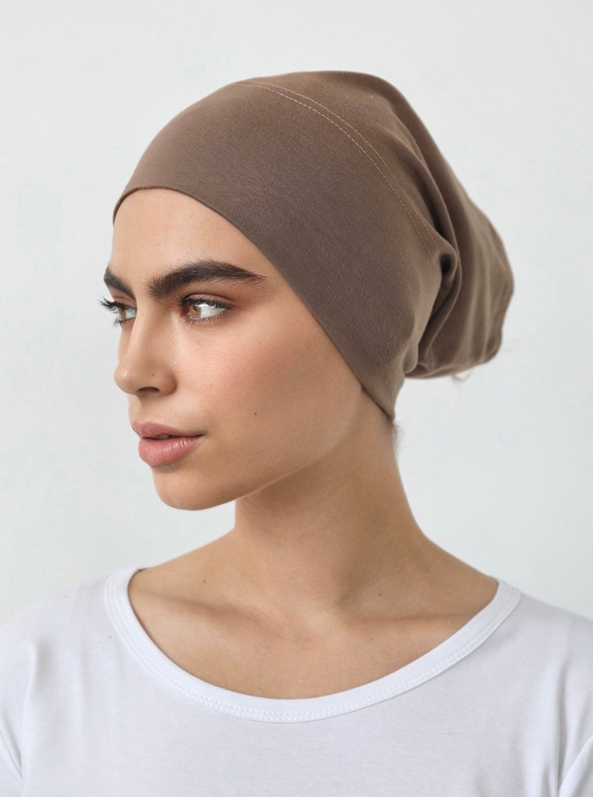 Model wearing a closed under-scarf cap (Veil of Faith) designed to cover hair under a scarf, made from soft natural fibres with a cotton-spandex blend for a comfortable, non-slip fit suitable for all-day wear.